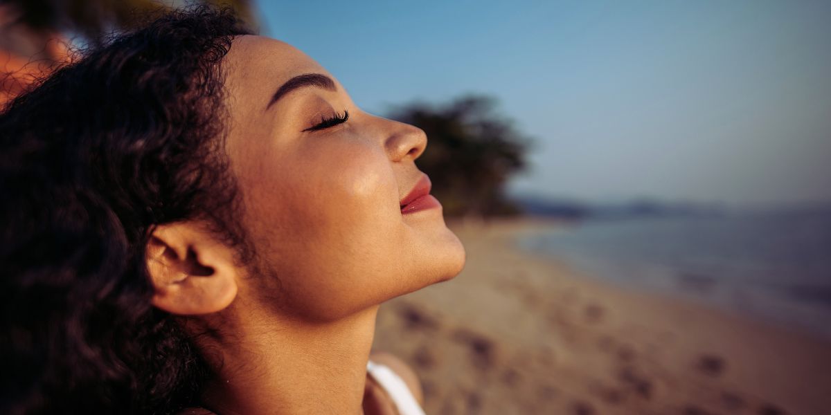 techniki oddechowe - kobieta na plaży głęboko oddycha